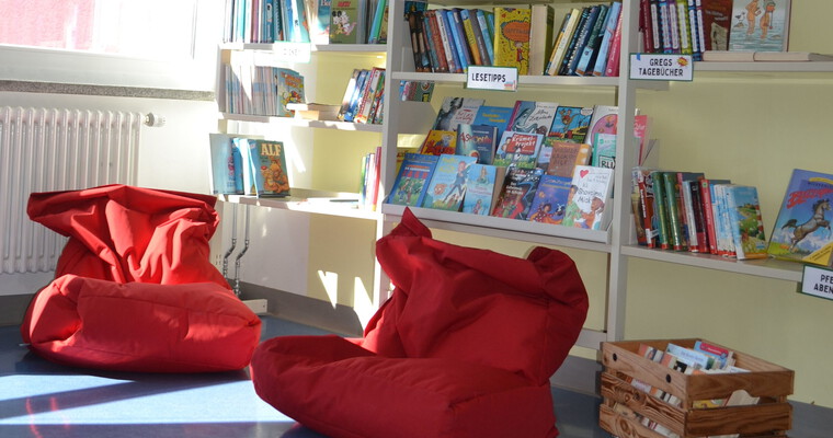 zwei rote Sitzsäcke vor Bücherregalen
